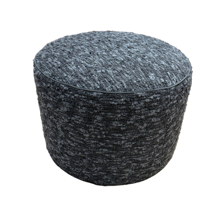 Round gray textured ottoman on a beige carpeted floor.